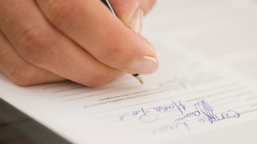 Stift liegt in der rechten Hand und schreibt auf einem Formular Stift liegt in der rechten Hand und schreibt auf einem Formular